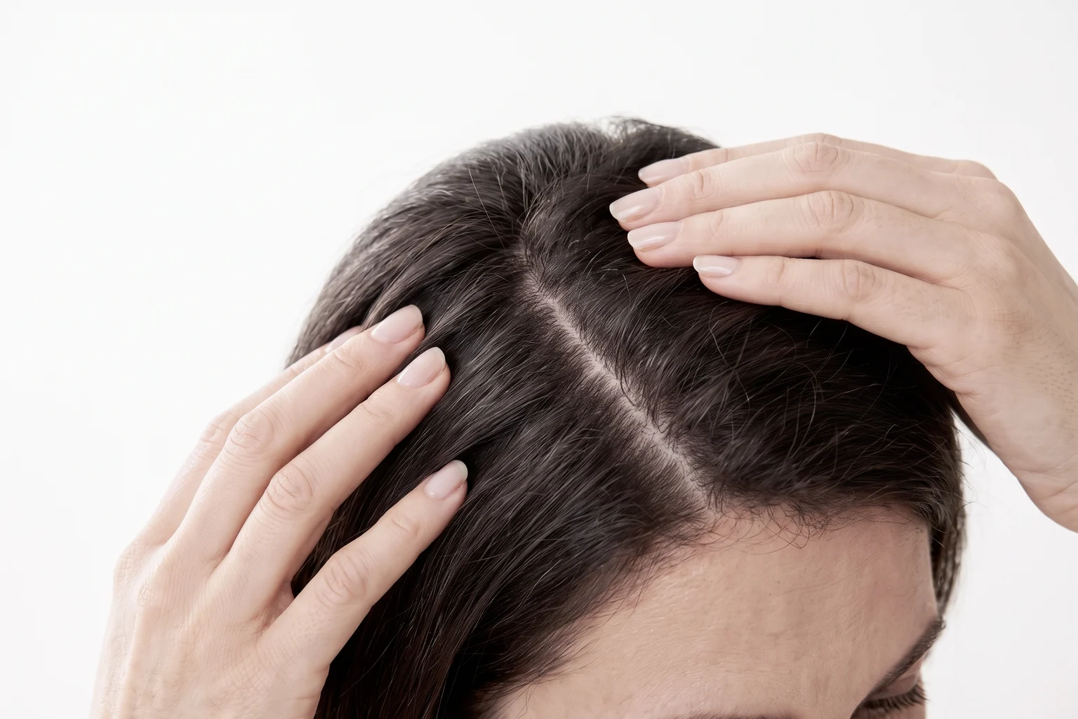 Woman gently parting her hair at the scalp
